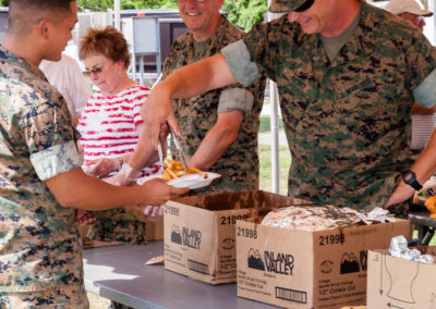 marines serving fish fry to a younger marine