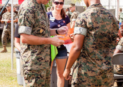 Two marines handing each other raffle tickets
