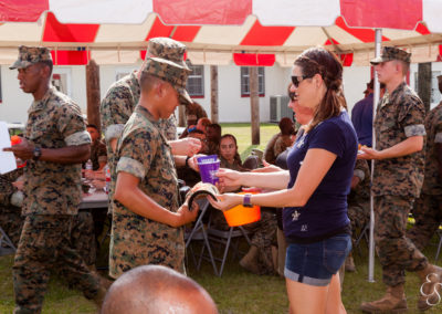women handing items to marines